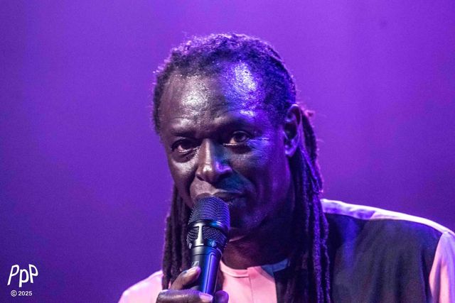 Portrait rapproché de Zale Seck au micro, éclairé de bleu et de violet.